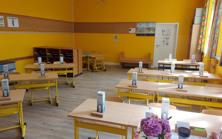 Ein Klassenzimmer ohne Schüler. Vor jedem Tisch steht eine neue Trinkflasche.