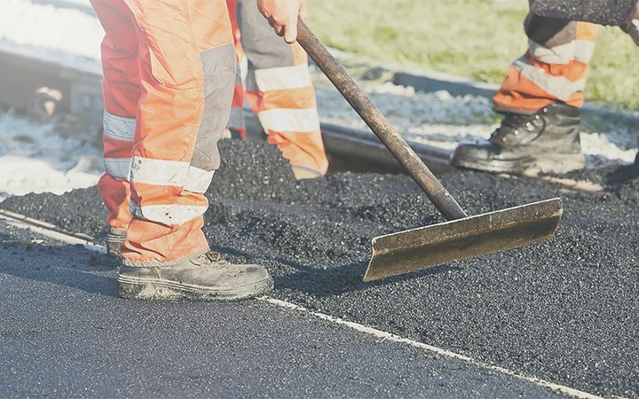 Asphalt wird mithilfe eines Werkzeugs glattgestrichen