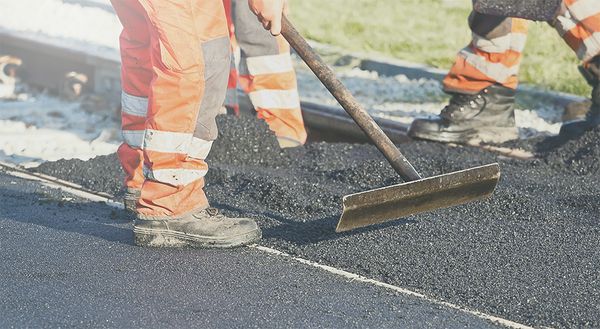 Asphalt wird mithilfe eines Werkzeugs glattgestrichen