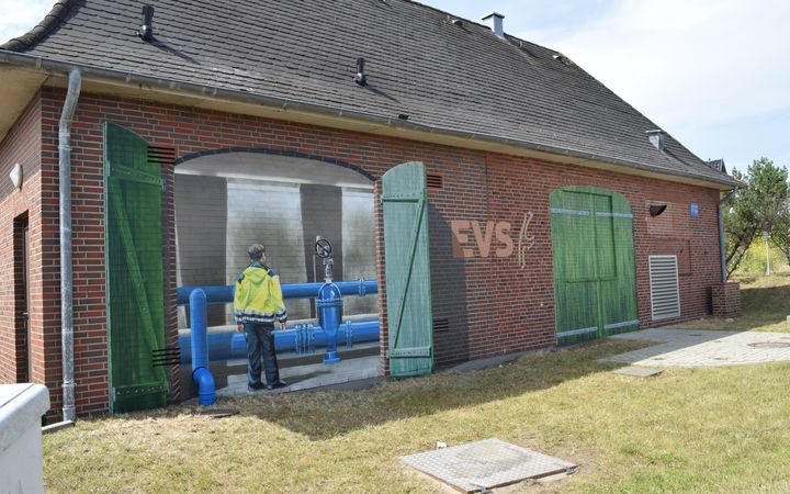 Ein großes Gebäude bemalt mit geöffneten Türen und dem Blick ins Innere