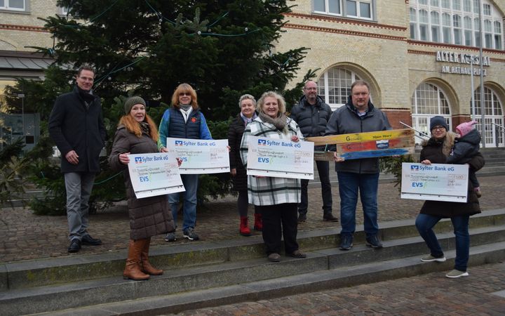 Menschen halten exemplarische Schecks der EVS in den Händen.