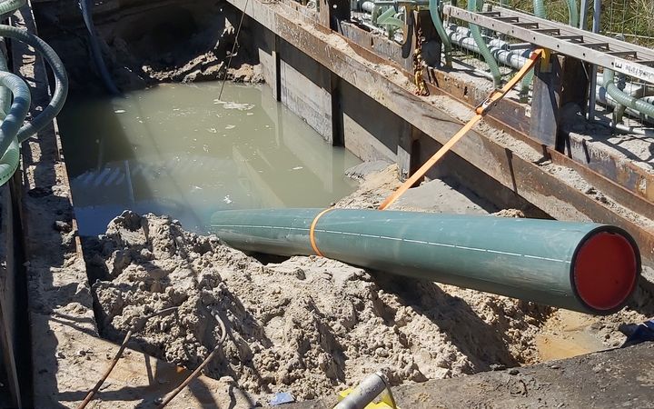 Ein Rohr ist teilweise in einem Erdloch versenkt, welches mit Wasser gefüllt ist