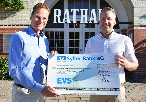 Zwei Männer mit einem Scheck für die Stiftung "Familien in Not"