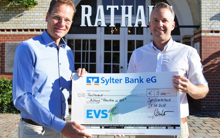 Zwei Männer mit einem Scheck für die Stiftung "Familien in Not"